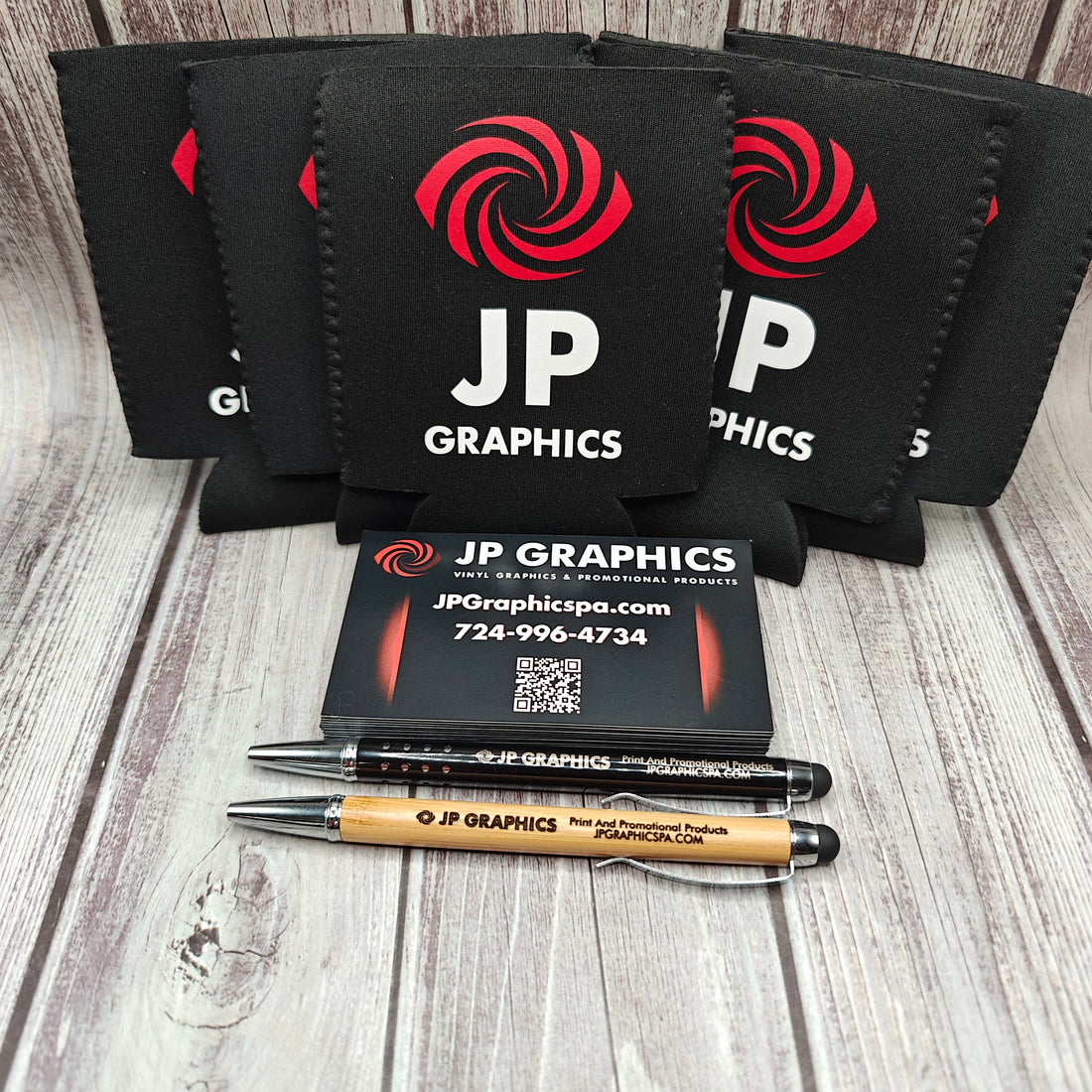 Collection of promotional products including can coolers, magnets, and pens