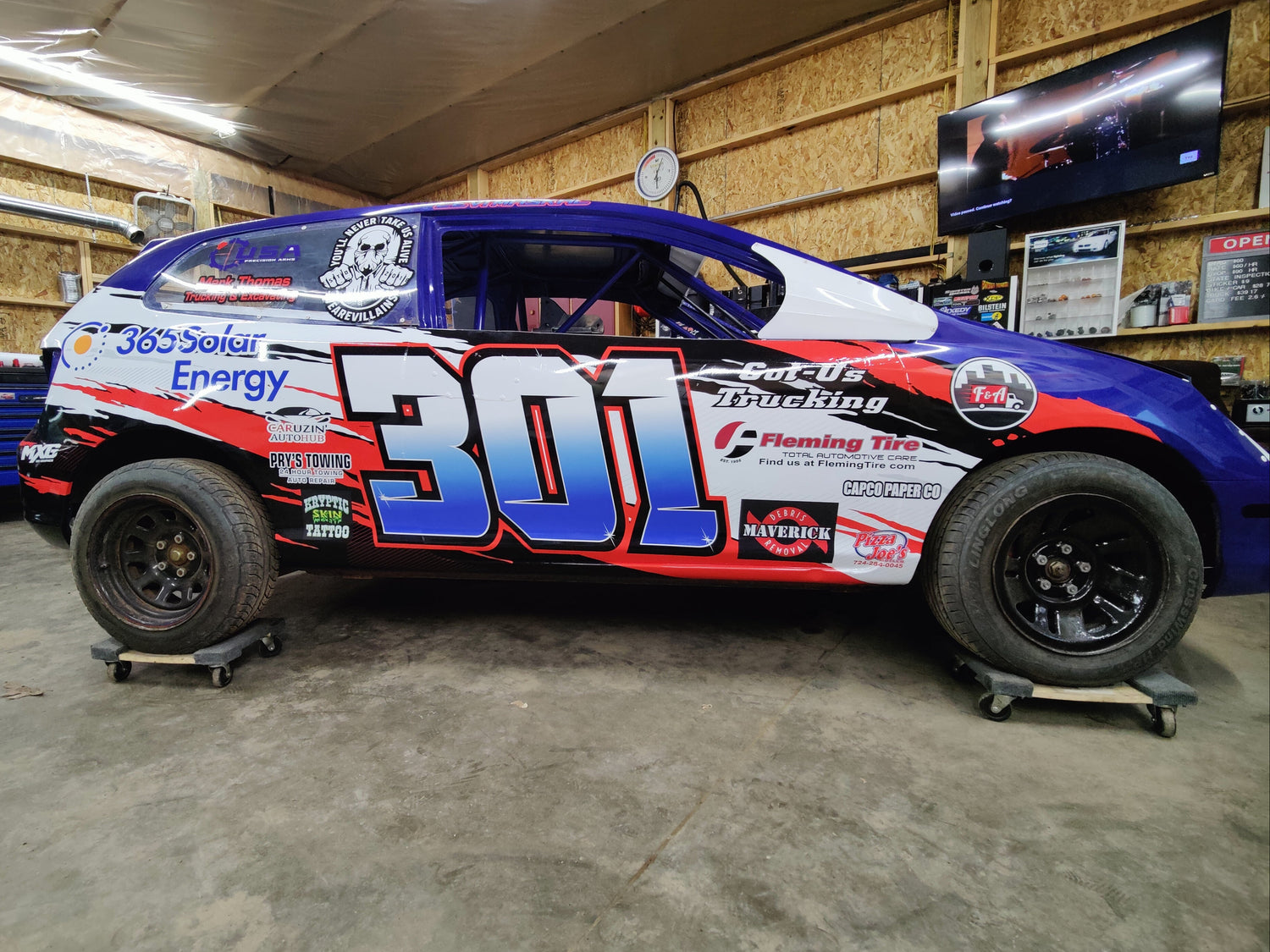 Colorful race car with number 301 in a garage setting
